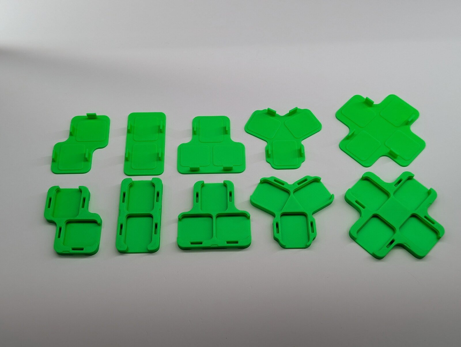 Real green printed joiner bases and separate caps, from left: L, straight, T, Y and X.
